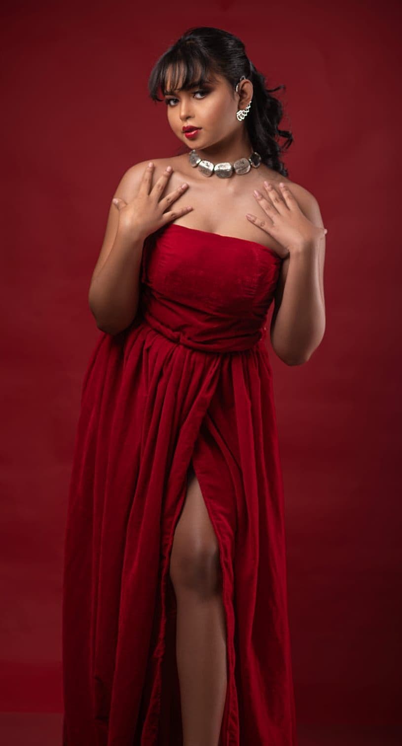 Sanjana Murmu in a full-length red gown with a silver plate choker, hands crossed at her chest.