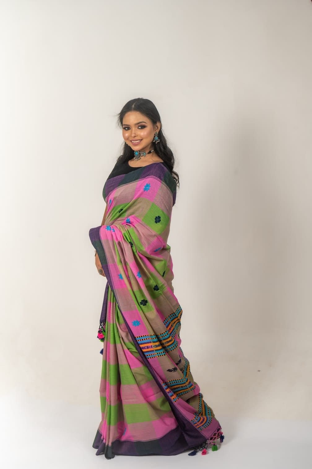 Sanjana Murmu in a pink and green handloom saree with a black blouse, seen full length against a pale ground.
