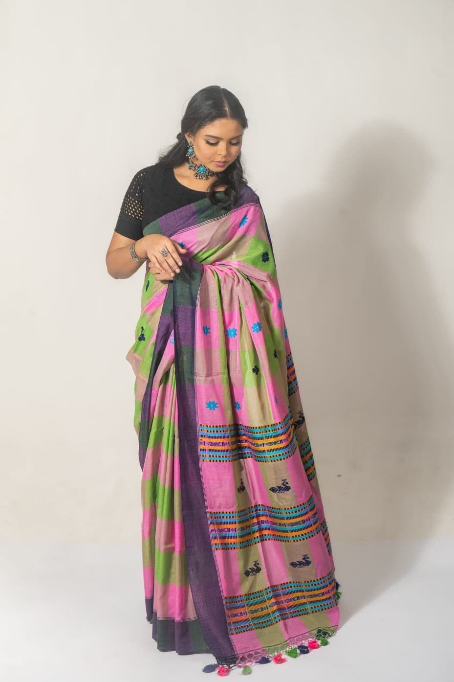 Sanjana Murmu adjusting the pleats of a pink and green handloom saree.