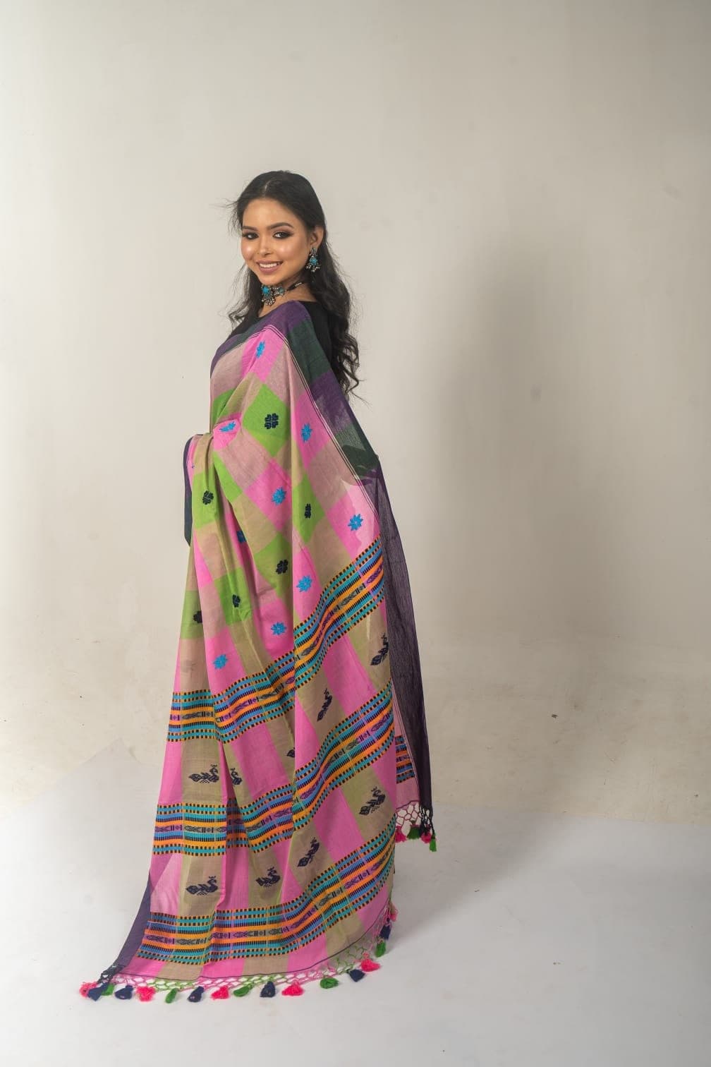 Sanjana Murmu in a pink and green handloom saree with tasselled border, seen from the side.