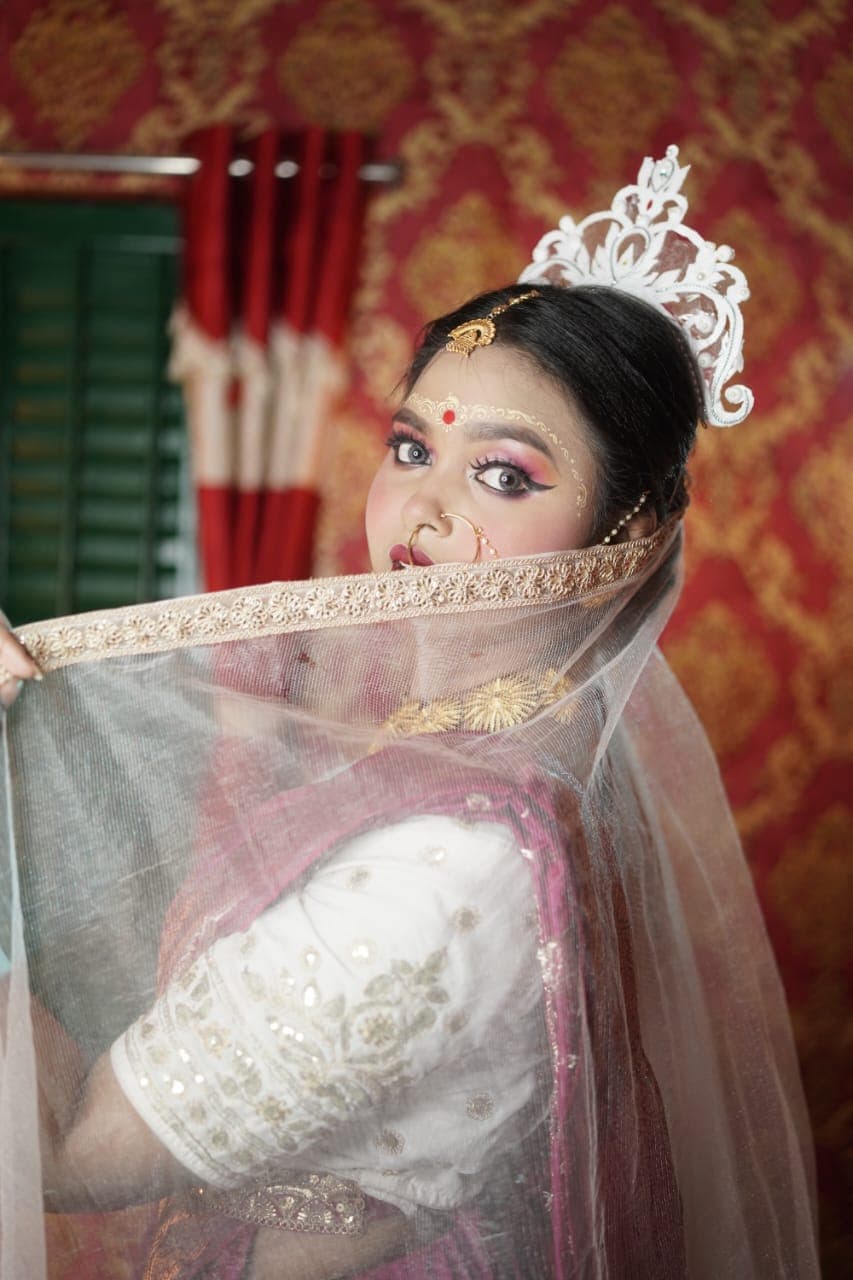 Sanjana Murmu drawing a sheer veil across her shoulder, gold bangles at both wrists.