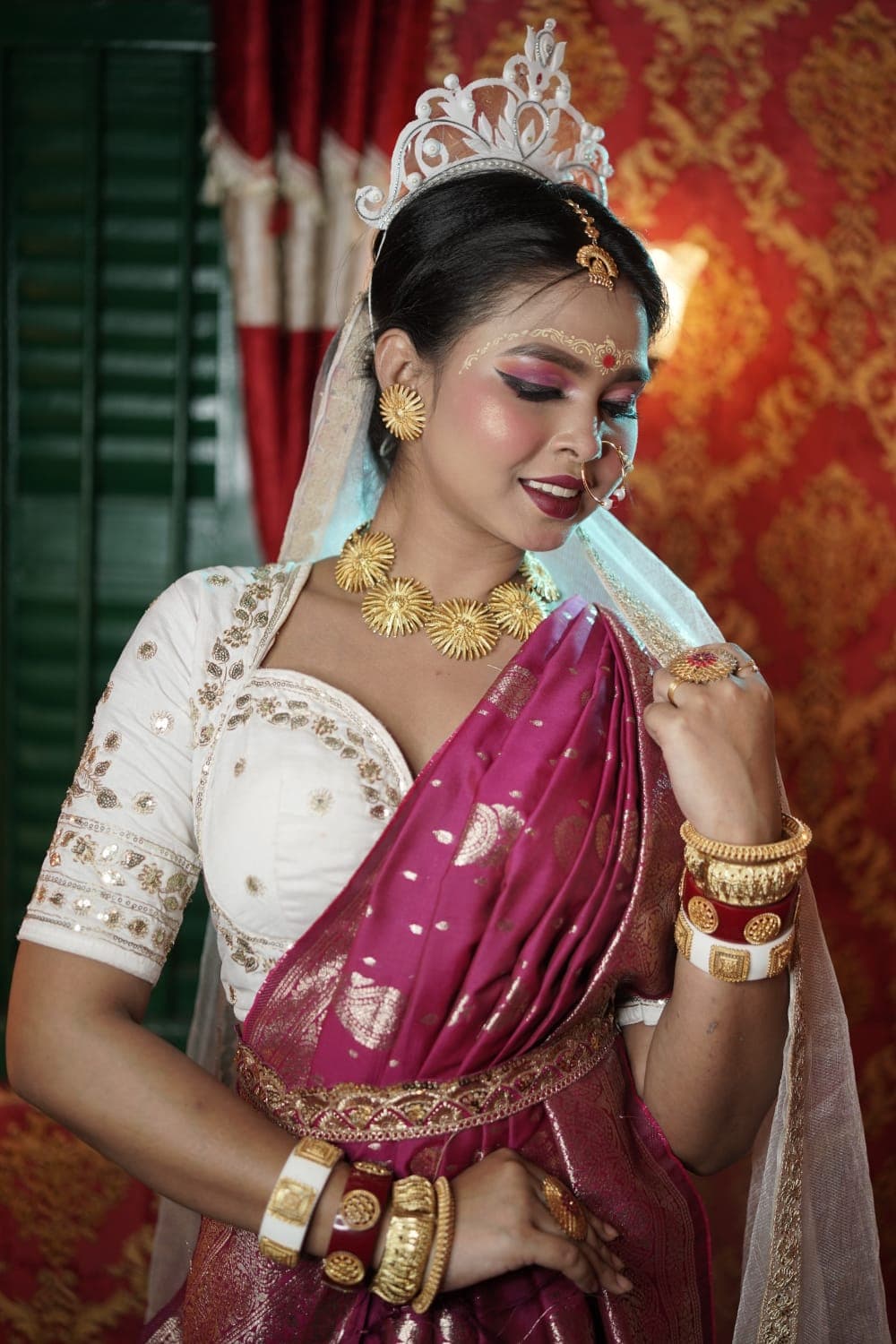 Sanjana Murmu with a hand at her waist, looking down, green shutters and red drapes behind her.