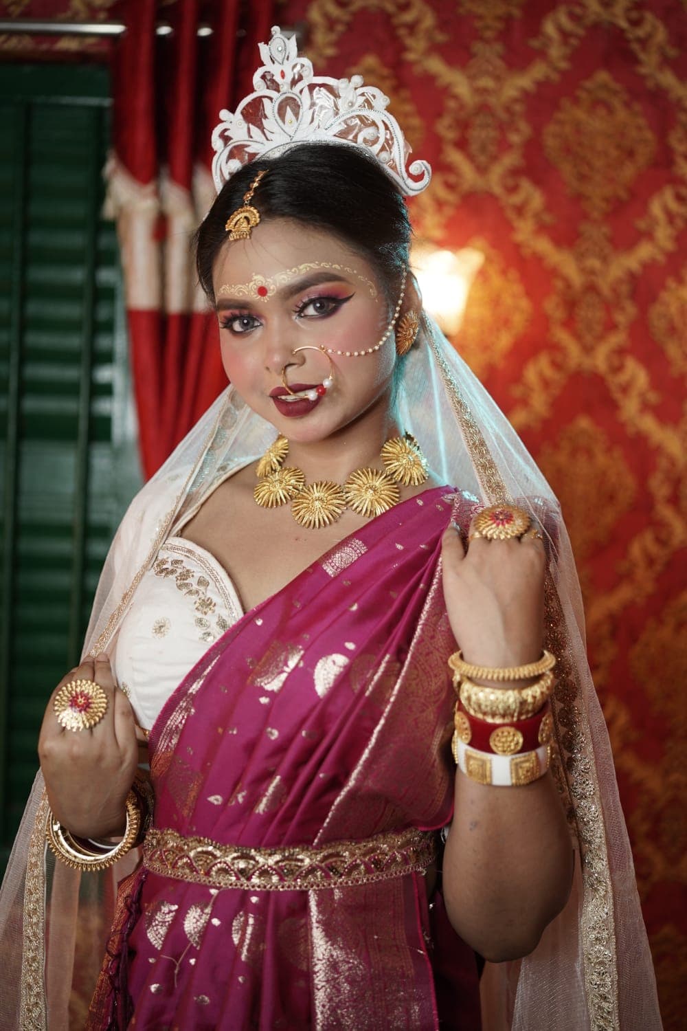 Sanjana Murmu looking down with a hand at her shoulder, veil catching warm light.