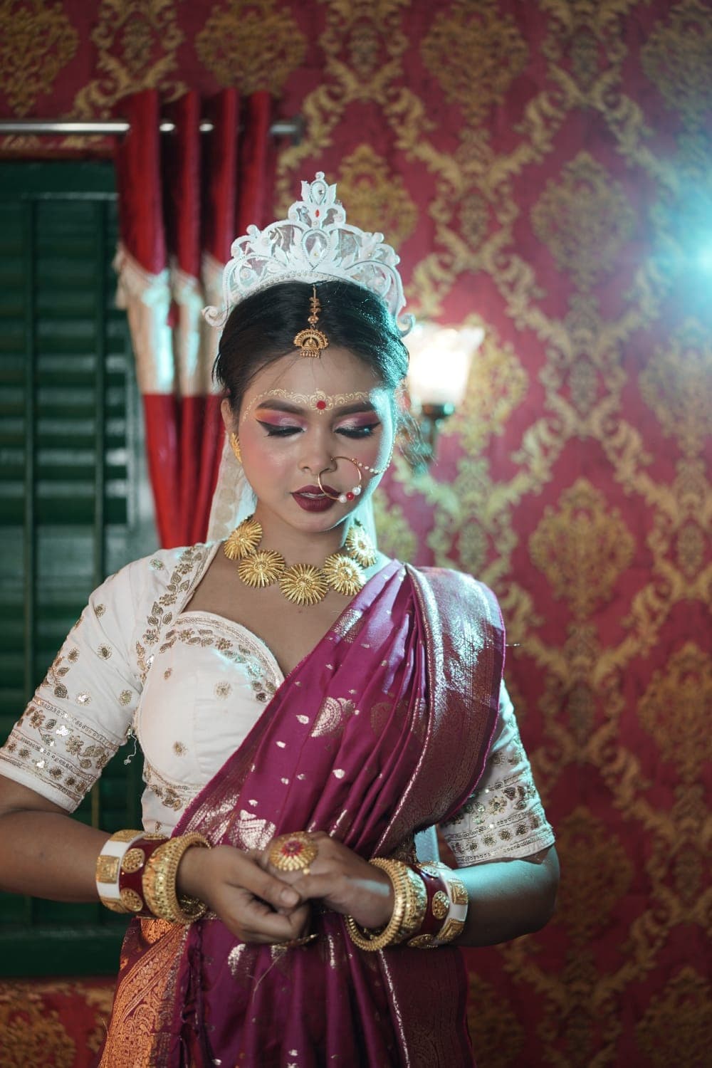Sanjana Murmu with her hands held together, lit by a cool rim light against a red and gold interior.