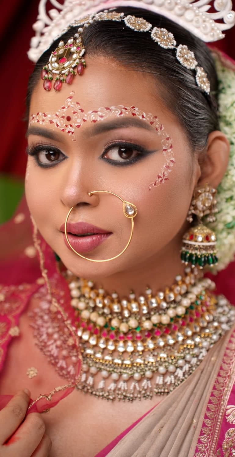 Sanjana Murmu in bridal makeup with a kundan nose ring and forehead ornament, jasmine at her hair.